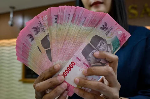 Seorang penukar uang menghitung uang kertas Rupiah di kantor penukaran uang di Jakarta,  Selasa (12/05/2026).