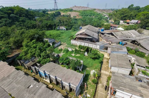Rumah-rumah warga yang sebagian sudah dibiarkan kosong akibat kerapkali banjir karena luapan Pesanggrahan yang alirannya menyempit karena longsoran TPA Cipayung  dengan latar belakang TPA Cipayung di Perumahan Griya Alif, Sawangan, Depok, Kamis (14/05/2026).
