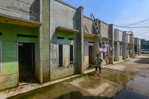 Warga berjalan melewati rumah yang ditinggal pergi pemiliknya akibat kerapkali banjir karena luapan Pesanggrahan yang alirannya menyempit karena longsoran TPA Cipayung di Perumahan Griya Alif, Sawangan, Depok, Kamis (14/05/2026).