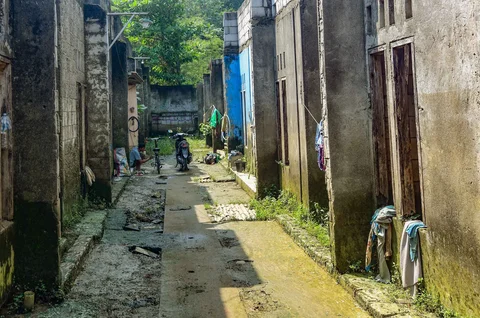 Warga memperbaiki sepedanya dengan deretan rumah yang ditinggal pemiliknya akibat kerapkali banjir karena luapan Pesanggrahan yang alirannya menyempit karena longsoran TPA Cipayung di Perumahan Griya Alif, Sawangan, Depok, Kamis (14/05/2026).