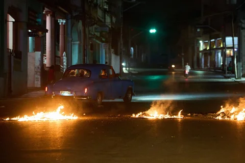 Warga mengendarai mobil klasik Amerika melewati barikade yang didirikan oleh warga yang memprotes pemadaman listrik berkepanjangan di Havana, Kuba, Rabu malam, (14/05/2026).