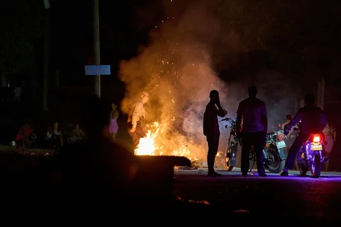 Seorang polisi berusaha memadamkan api yang dinyalakan oleh warga yang memprotes pemadaman listrik berkepanjangan di jalanan Havana, Kuba, Kamis malam (14/05/2026).