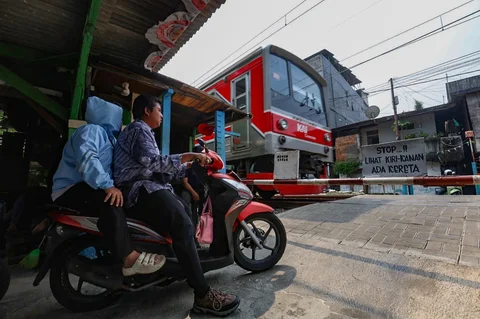 Pengendara menggu krl lewat di perlintasan liar jalur kereta api di kawasan Tebet, Jakarta, Jumat(15/05/2026).