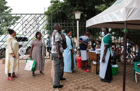 Orang-orang menunggu untuk diperiksa suhu tubuhnya di depan Rumah Sakit Muslim Kibuli di Kampala, Uganda, Sabtu, (16/05/2026).