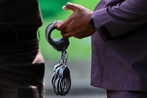 Seorang petugas penegak hukum memegang borgol saat hukuman cambuk di depan umum di Banda Aceh, Kamis (21/5/2026).