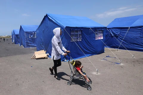 Warga berjalan melewati tenda biru bantuan pemerintah Lebanon di Beirut, Jumat (22/05/2026).