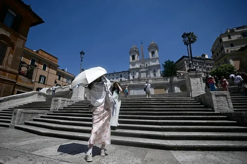 Para wisatawan melindungi diri dari terik matahari dengan payung saat berdiri di Tangga Spanyol selama gelombang panas awal musim di Roma Selasa (26/05/2026).