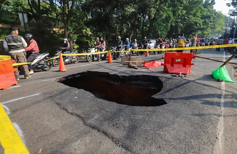 Pengendara bermotor melintas pada jalan yang ditutup sebagian  akibat jalan yang amblas di Jalan Raya Lenteng Agung, Jakarta Selatan, Jumat (29/5/2026).