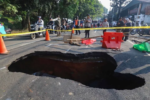 Pengendara bermotor melintas pada jalan yang ditutup sebagian  akibat jalan yang amblas di Jalan Raya Lenteng Agung, Jakarta Selatan, Jumat (29/5/2026).