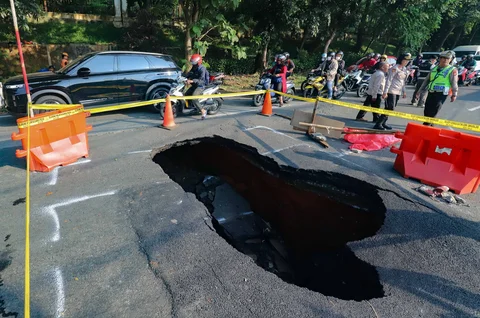 Pengendara bermotor melintas pada jalan yang ditutup sebagian  akibat jalan yang amblas di Jalan Raya Lenteng Agung, Jakarta Selatan, Jumat (29/5/2026).
