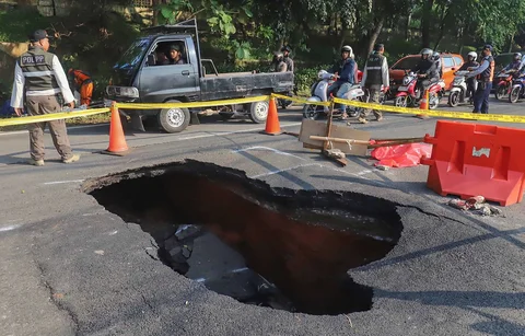 Pengendara bermotor melintas pada jalan yang ditutup sebagian  akibat jalan yang amblas di Jalan Raya Lenteng Agung, Jakarta Selatan, Jumat (29/5/2026).