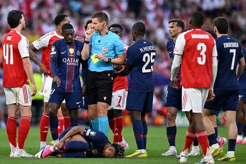 Wasit Jerman Daniel Siebert memegang kartu kuning setelah pelanggaran yang dilakukan oleh gelandang Inggris Arsenal Bukayo Saka terhadap penyerang Prancis Paris Saint-Germain Desire Doue (bawah) selama pertandingan final Liga Champions UEFA antara Paris Saint-Germain (PSG) dan Arsenal FC di Puskas Arena di Budapest,  Minggu (31/05/2026).