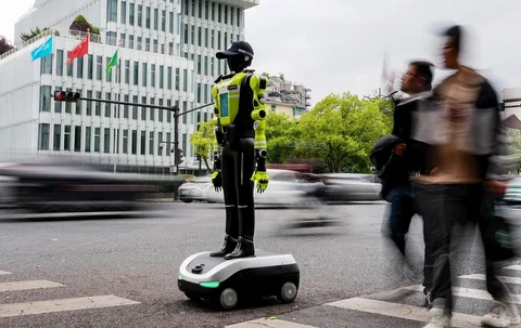Orang-orang berjalan melewati robot polisi humanoid di Hangzhou, provinsi Zhejiang timur Tiongkok, Minggu (03/05/2026