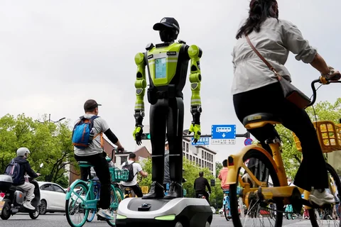 Orang-orang berjalan melewati robot polisi humanoid di Hangzhou, provinsi Zhejiang timur Tiongkok, Minggu (03/05/2026