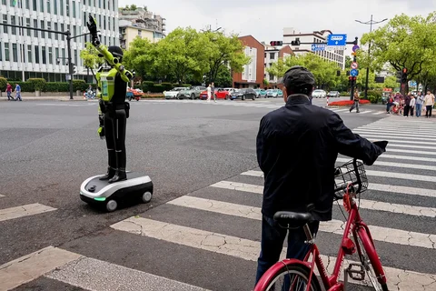 Orang-orang berjalan melewati robot polisi humanoid di Hangzhou, provinsi Zhejiang timur Tiongkok, Minggu (03/05/2026
