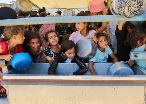 Anak-anak Palestina menunggu makanan di dapur amal di daerah Mawasi, Khan Yunis, Jalur Gaza Selatan, Selasa (22/07/2025).<br />AFP