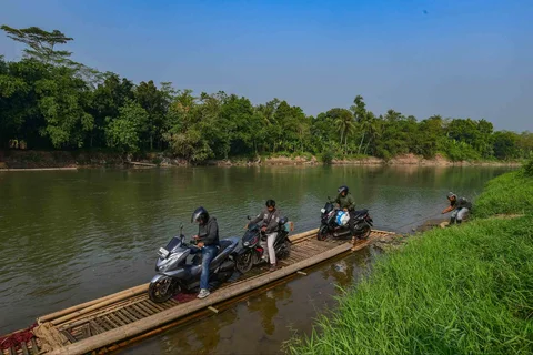 Warga dengan kendaraan motornya menggunakan rakit bambu untuk menyeberangi Sungai Cisadane di kawasan Ciseeng, Bogor, Jawa Barat, Kamis (11/06/2026).