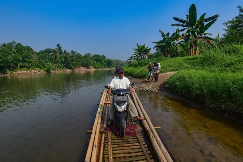 Warga dengan kendaraan motornya menggunakan rakit bambu untuk menyeberangi Sungai Cisadane di kawasan Ciseeng, Bogor, Jawa Barat, Kamis (11/06/2026).