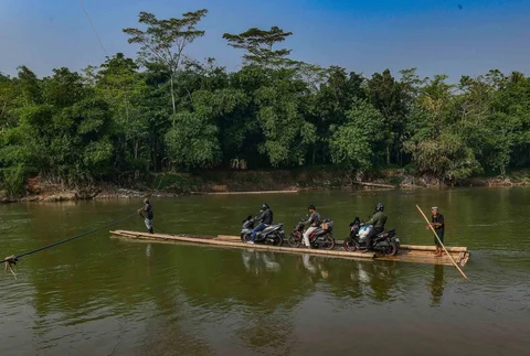 Warga dengan kendaraan motornya menggunakan rakit bambu untuk menyeberangi Sungai Cisadane di kawasan Ciseeng, Bogor, Jawa Barat, Kamis (11/06/2026).