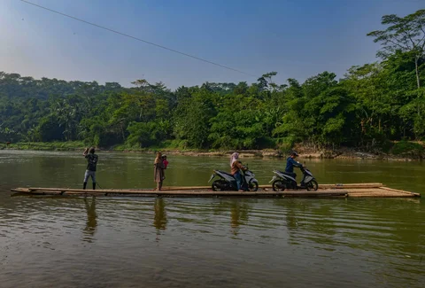 Warga dengan kendaraan motornya menggunakan rakit bambu untuk menyeberangi Sungai Cisadane di kawasan Ciseeng, Bogor, Jawa Barat, Kamis (11/06/2026).