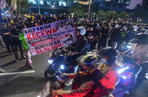 Pengunjuk rasa membentangkan spanduk meminta dukungan klakson kepada pengendara bermotor di Jalan MH. Thamrin, Jakarta, Jumat (12/06/2026).