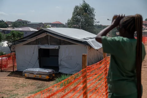 Seorang pengawas kamar mayat di Pusat Medis Injili Nyankunde (CME) mengamati dari kejauhan saat peti mati berdiri di luar pintu masuk kamar mayat di Bunia, Provinsi Ituri, Republik Demokratik Kongo, Sabtu (13/06/2026).