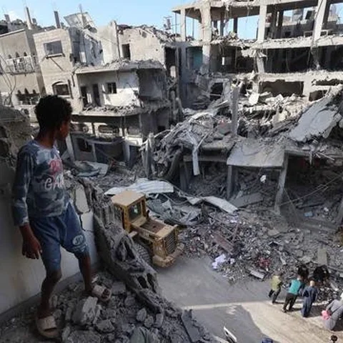 Seorang anak laki-laki Palestina yang mengungsi melihat bangunan yang rusak akibat serangan Israel di kamp pengungsi Maghazi, Jalur Gaza Tengah pada Kamis 21 Mei 2026. (Eyad Baba/AFP)