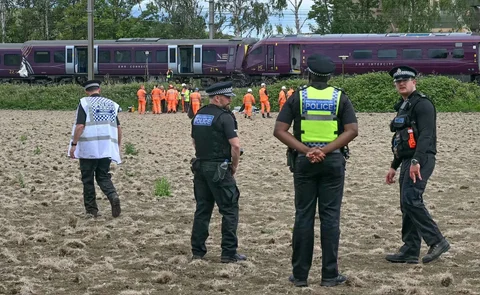 Petugas Kepolisian Transportasi Inggris berjaga di lokasi kecelakaan sementara tim Cabang Investigasi Kecelakaan Kereta Api melakukan penyelidikan terhadap tabrakan dua kereta East Midlands Railway (EMR) di selatan Bedford, Inggris tengah, Sabtu (20/06/2026).