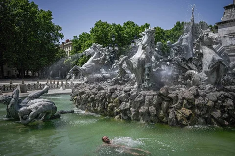 Seorang pria mendinginkan diri di kolam air mancur Girondins di Place des Quinconces saat Prancis dilanda gelombang panas, di Bordeaux, Prancis barat daya, Senin (22/06/2026).