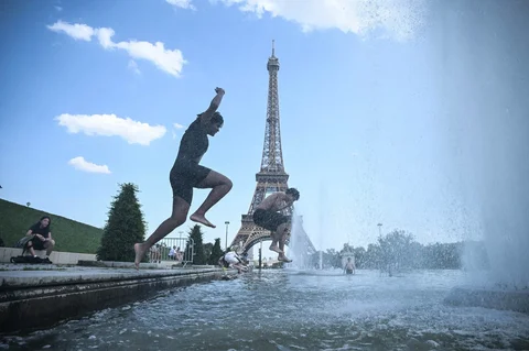 Orang-orang melompat ke Air Mancur Trocadero di dekat Menara Eiffel selama gelombang panas di Paris, Prancis Senin (22/06/2026).