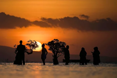 Warga berdiri di air dekat pohon bakau saat matahari terbenam di pantai Walakiri di Waingapu, Sumba Timur, Nusa Tenggara Timur, Rabu (24/06/2026).