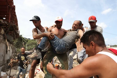 Warga sekitar menggendong seorang pria yang diselamatkan dari reruntuhan bangunan yang runtuh sehari setelah gempa bumi melanda La Guaira, Venezuela, Kamis (25/06/2026).