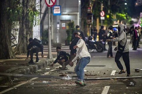 Seorang mahasiswa melempar batu ke arah polisi anti huru hara saat protes terhadap kenaikan harga bahan bakar non-subsidi, pengeluaran pemerintah yang tidak efisien, keterlibatan militer dalam urusan sipil, dan program makan siang gratis (MBG) pemerintah di depan Gedung Grahadi Surabaya, Jumat malam (26/06/2026).