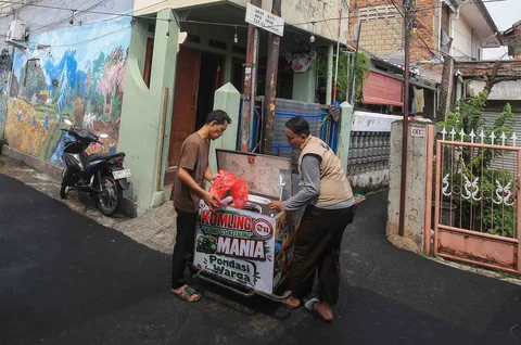 Petugas melayani warga yang membuang sampah organik pada gerobak listrik Komling (kompos keliling) di Rt  11/ 07, Gandarai Utara, Jakarta, Minggu (28/06/2026).