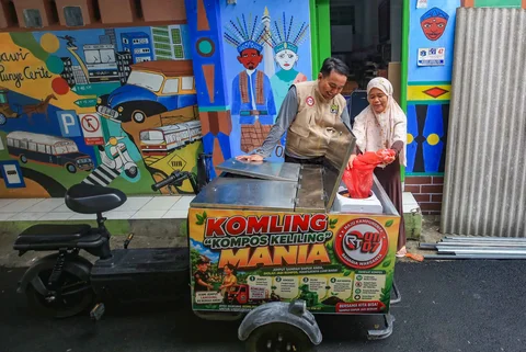 Petugas melayani warga yang membuang sampah organik pada gerobak listrik Komling (kompos keliling) di Rt  11/ 07, Gandarai Utara, Jakarta, Minggu (28/06/2026).