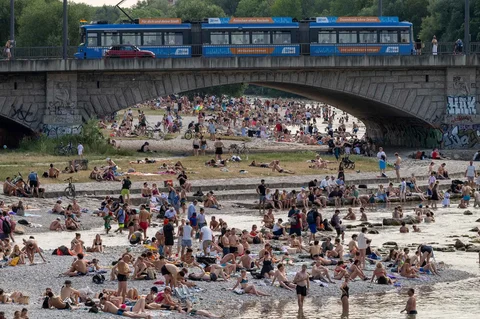 Para perenang menikmati kesejukan di perairan Sungai Isar dan di tepian kerikil di sekitar Jembatan Reichenbach di Munich, Jerman, Minggu (28/06/2026).