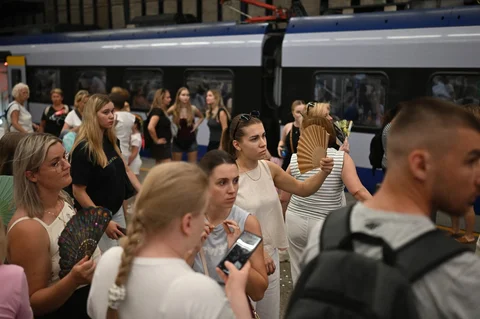 Penumpang menggunakan kipas tangan sambil menunggu kereta yang tertunda akibat gelombang panas di stasiun kereta api Warsawa Pusat di Warsawa, polandia, Minggu (28/06/2026).