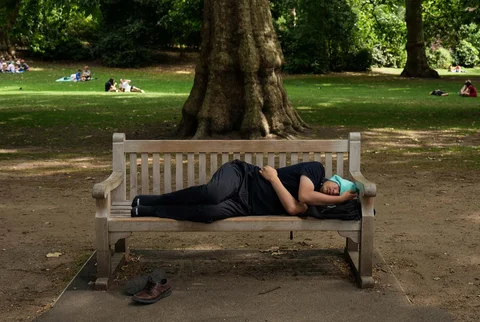 Seorang pria beristirahat di bangku taman di pusat kota London, Inggris, Minggu (28/06/2026).
