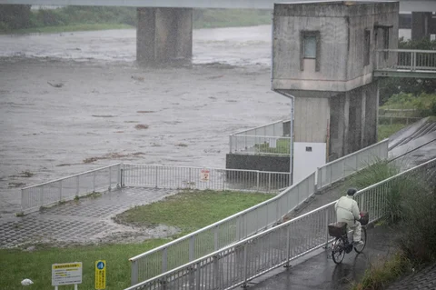 Warga bersepeda melewati sungai Tama di tengah hujan deras akibat badai tropis dahsyat Jangmi di Tokyo,  Rabu (03/06/2026).