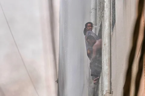 Sebuah keluarga warga negara asing bergelantungan di jendela  saat kebakaran hotel  di New Delhi, India, Rabu (03/06/2026).