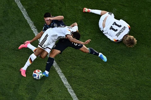 Pemain Jerman Jamal Musiala berebut bola dengan pemain Paraguay Braian Ojeda, sementara pemain Jerman, Nick Woltemade tergeletak di tanah selama pertandingan sepak bola babak 32 besar Piala Dunia 2026 antara Jerman dan Paraguay di Stadion Boston di Foxborough,  AS, Senin (29/06/2026).