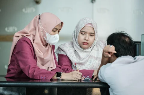 Para pekerja berbicara dengan seorang pelanggan di kantor penukaran mata uang di Jakarta, Kamis (04/06/2026).