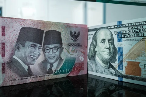 Uang kertas pecahan 100.000 rupiah Indonesia dipajang berdampingan dengan uang kertas pecahan 100 dolar AS di kantor penukaran mata uang di Jakarta,  Kamis (04/06/2026).