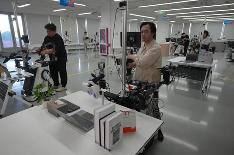 Para pelatih mengendalikan lengan robot di Pusat Data dan Pelatihan Robot Kecerdasan Buatan Terwujud (Embodied Artificial Intelligence Robot Data and Training Base) di Beijing E-Town di pinggiran Beijing, China (29/05/2026).