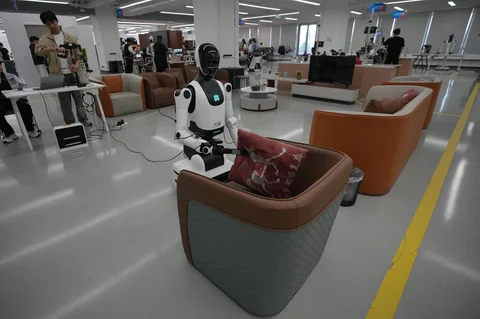 Seorang instruktur mengendalikan robot untuk merapikan bantal di sofa di Pusat Data dan Pelatihan Robot Kecerdasan Buatan Terwujud (Embodied Artificial Intelligence Robot Data and Training Base) di Beijing E-Town di pinggiran Beijing, China (29/05/2026).