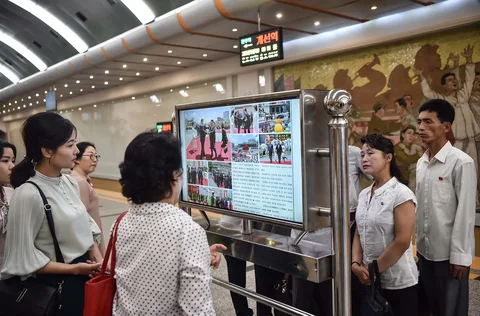 Orang-orang melihat layar yang menampilkan surat kabar "Rodongsinmun" yang memberitakan kunjungan Presiden Tiongkok Xi Jinping, di Stasiun Kaeson Metro Pyongyang di Pyongyang, Korea Utara, Selasa (09/06/2026).<br />AFP/ Kim Won Jin