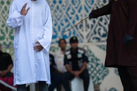 Algojo  mengeksekusi cambuk terhadap terpidana pelanggar hukum syariat Islam, diantaranya karena mencium seorang wanita saat siaran langsung TikTok, menjalani hukuman cambuk  di Taman Bustanussalatin, Banda Aceh, Aceh, Kamis (2/7/2026).