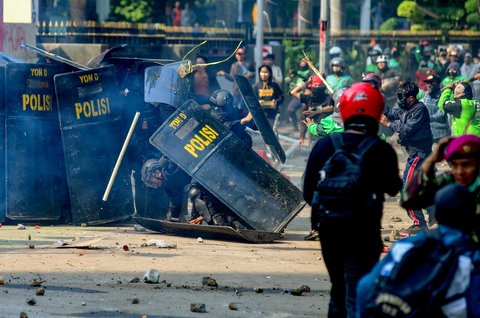 Anggota Brimob terjatuh saat massa melempar batu ke arah pasukan Brimob di Mako Brimob, Kwitang, jakarta, Jumat (29/08/2025).