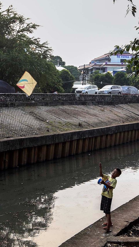 FOTO: Ruang Terbuka Hijau Minim, Anak-Anak di Jakarta Main Layang-Layang di Pinggir Kali