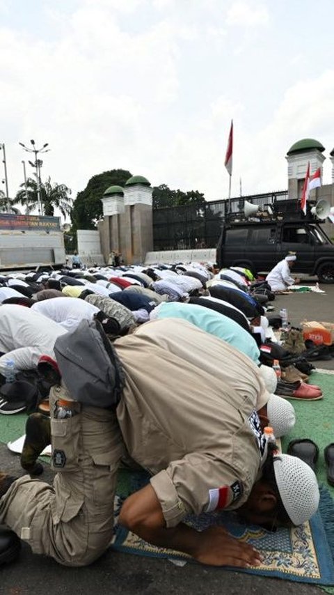 FOTO: Momen Pengunjuk Rasa Tuntut Hak Angket Gelar Jumatan di Depan Gedung DPR